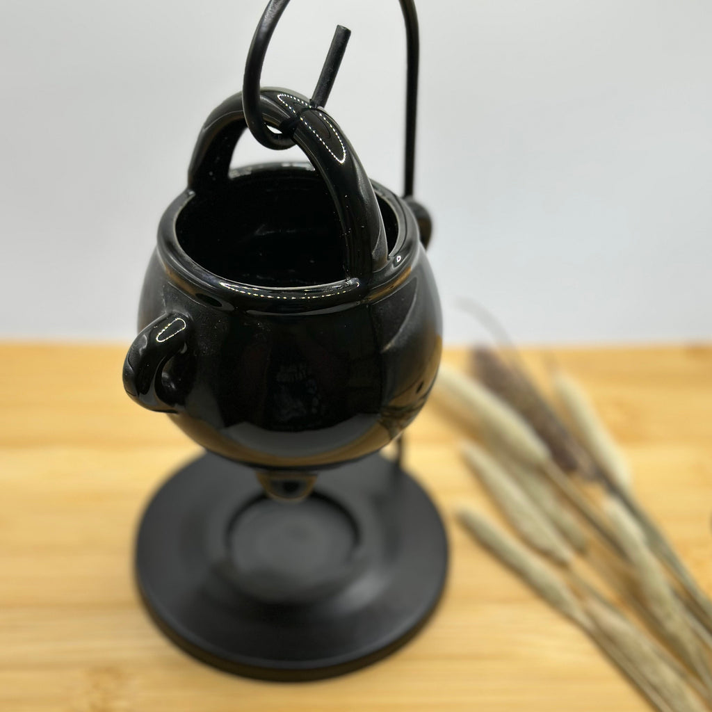 Bovenaanzicht van zwarte ketel waxbrander van keramiek, hangend in metalen houder met open schaaltje bovenin.