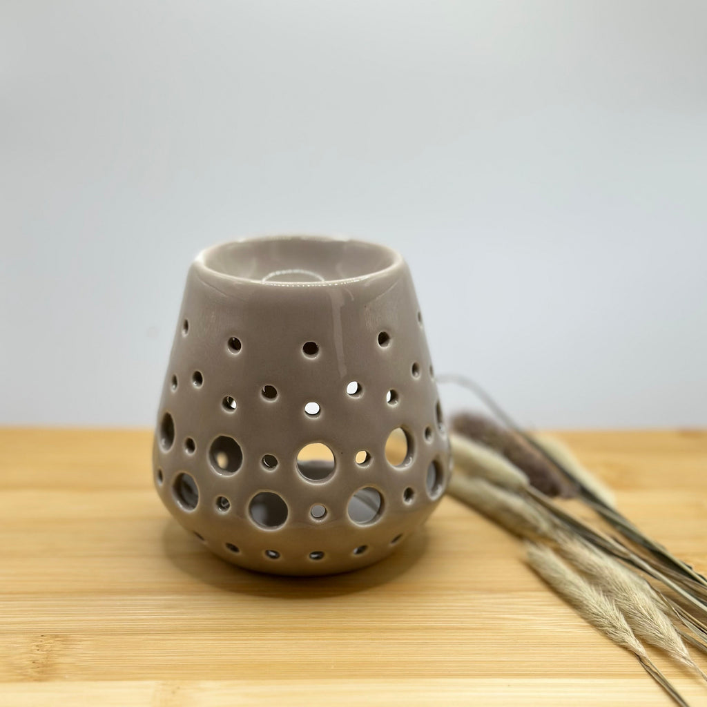 Grijze keramieken waxbrander met decoratieve ronde stippen openingen.