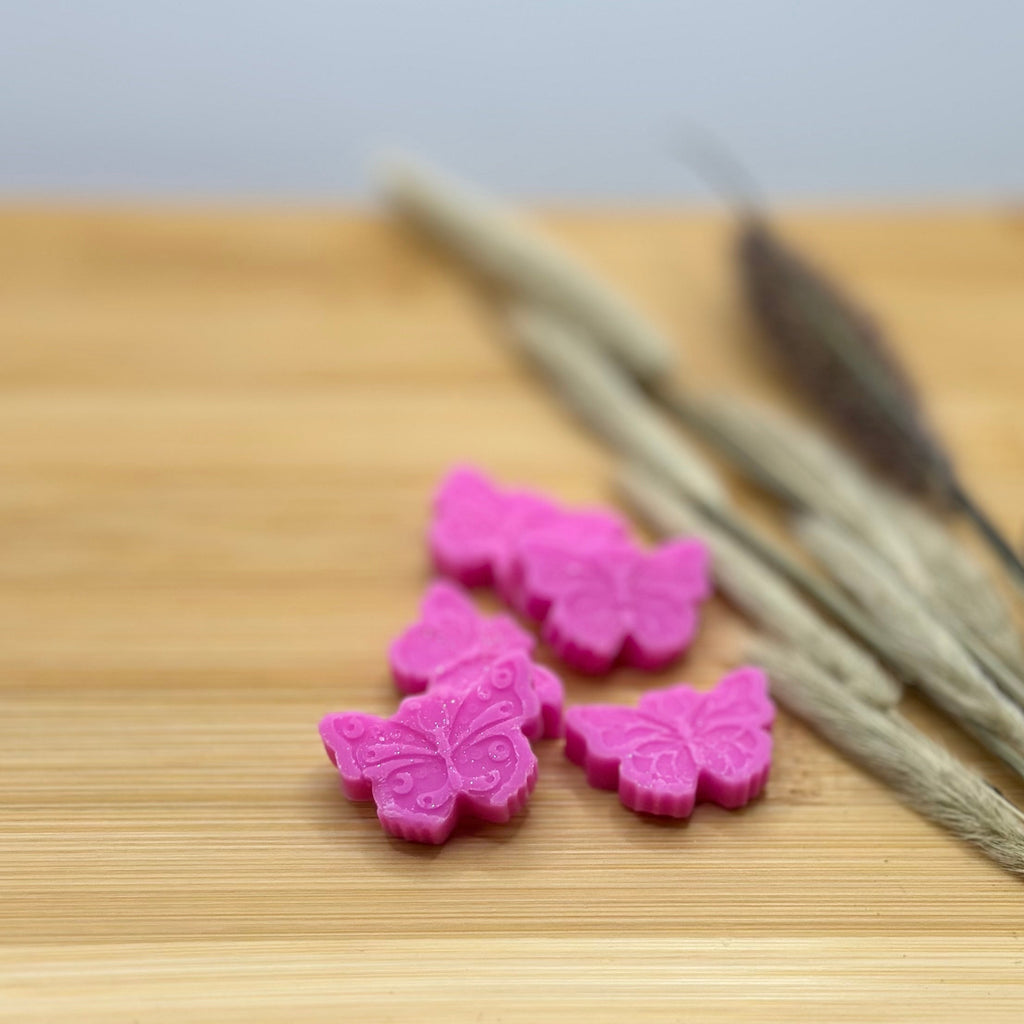Roze vlinder wax melts Magnolia Dream met magnolia geur op houten ondergrond