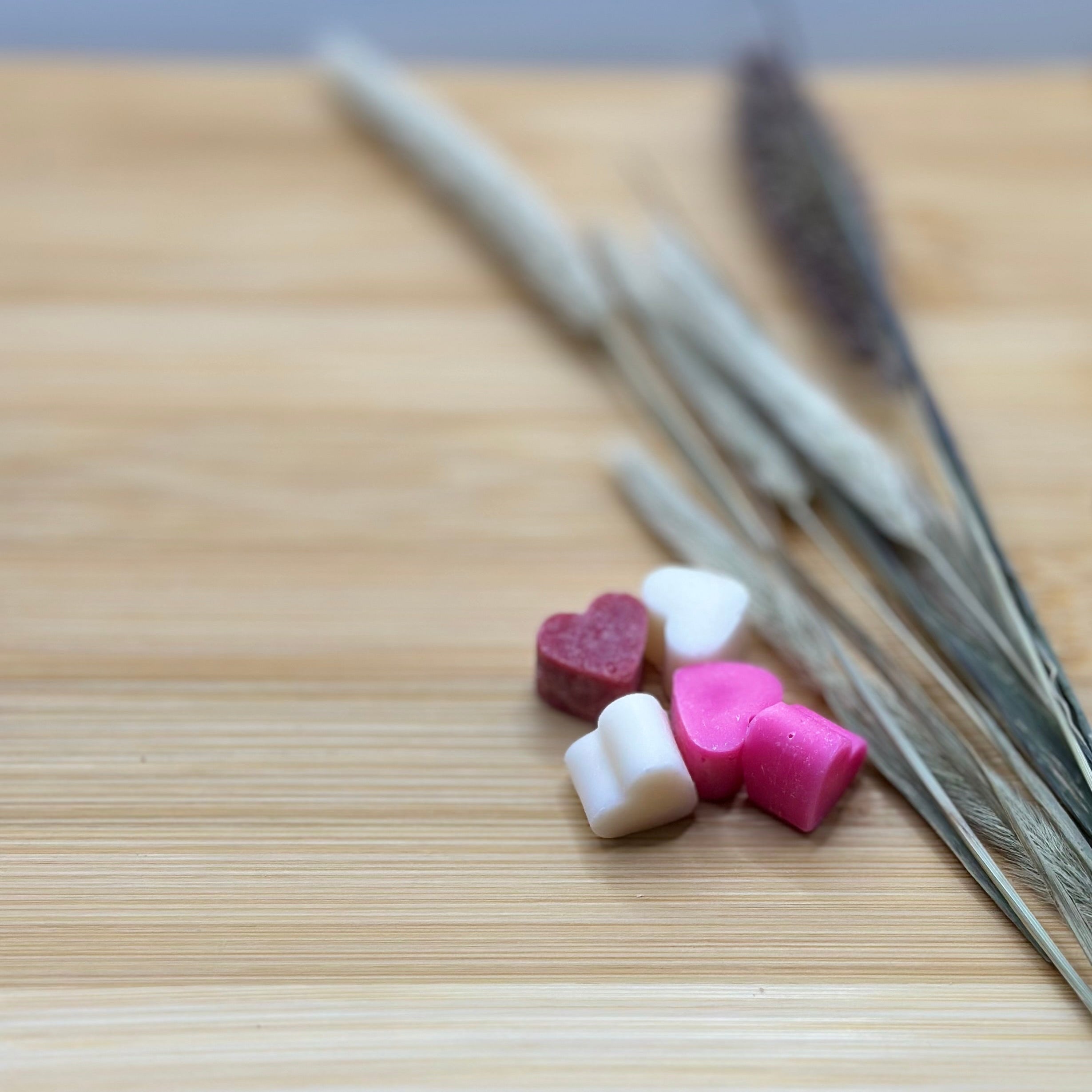 Roze, witte en rode hartjes wax melts Love Spell met zachte cashmere en rozengeur op houten ondergrond