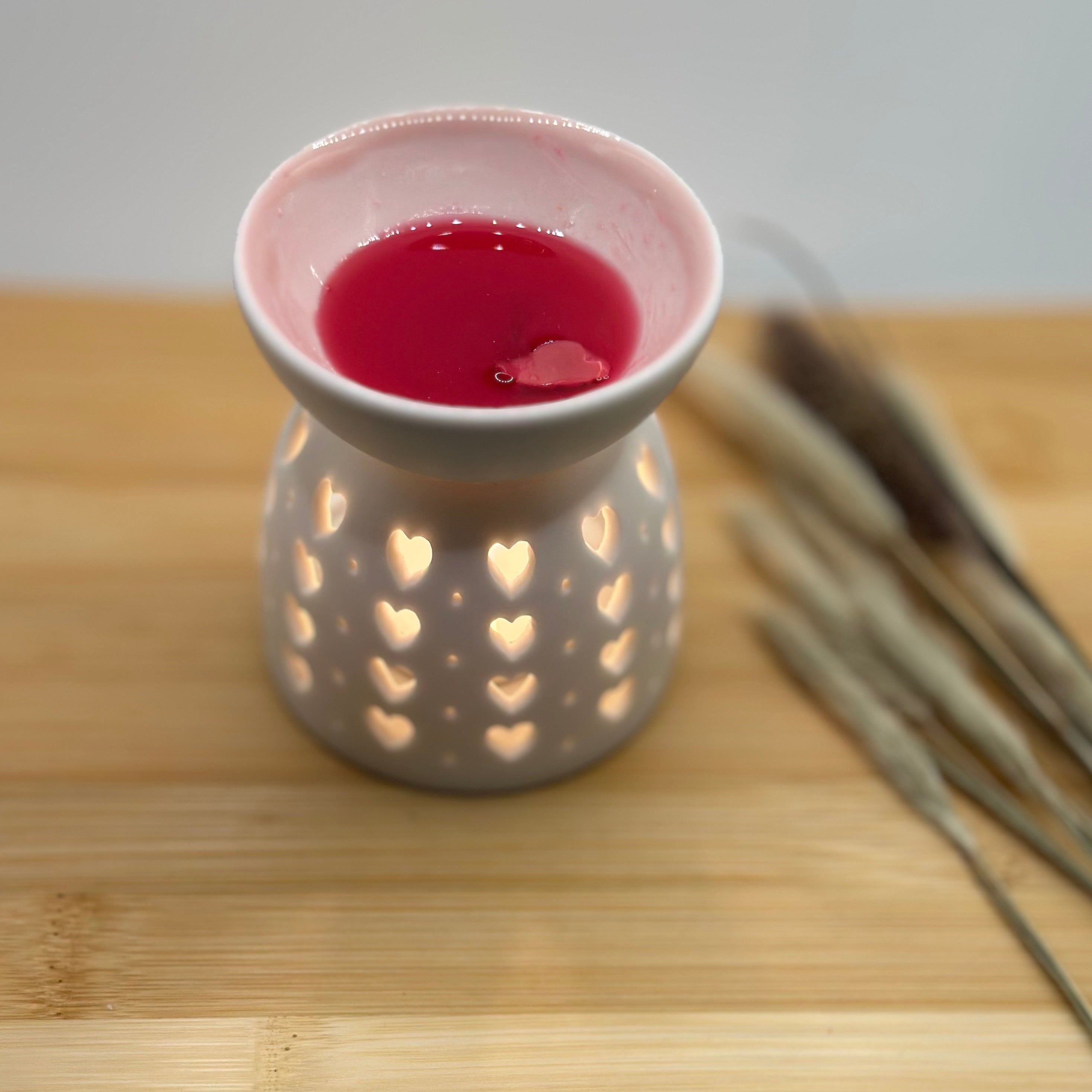 Witte hartjes waxbrander met gesmolten roze wax en warm licht van binnen.