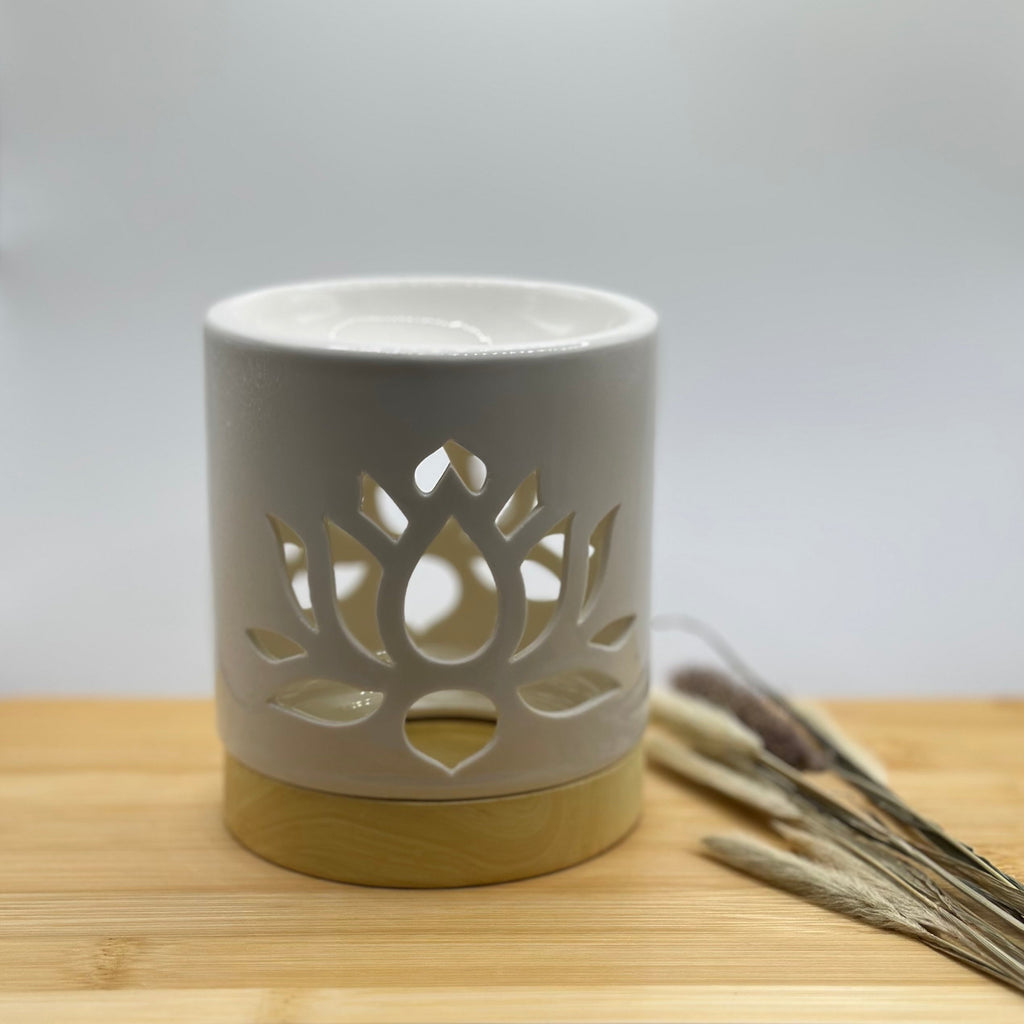 Witte keramieken waxbrander met uitgesneden lotusbloem en houtkleurige voet, bovenaan een wit schaaltje voor wax melts