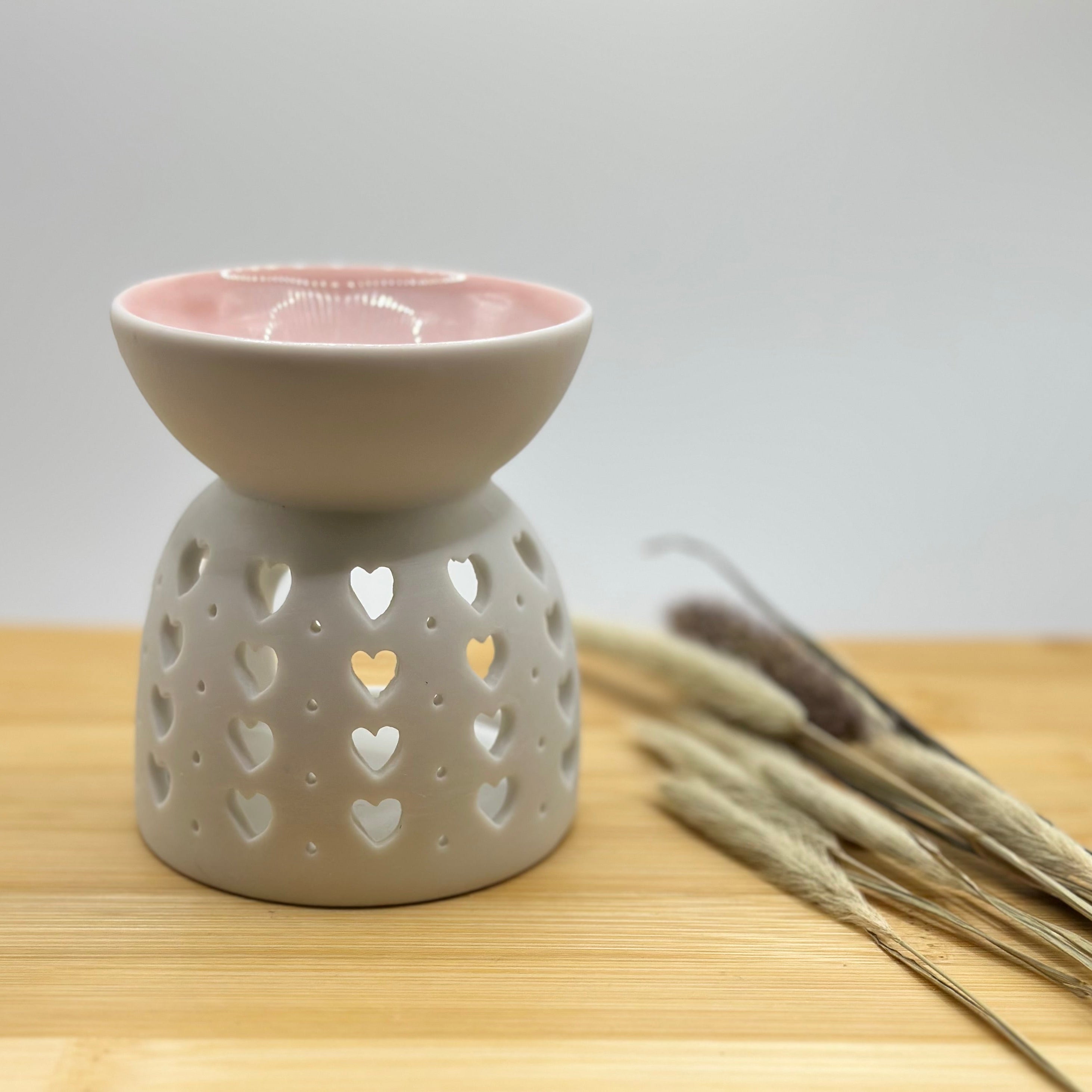 Witte waxbrander met hartjespatroon en zachtroze schaaltje bovenop.
